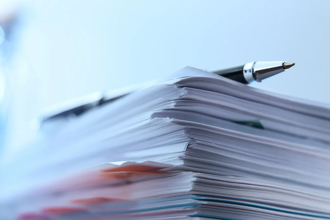 A pen resting on a stack of documents during a privacy impact assessment