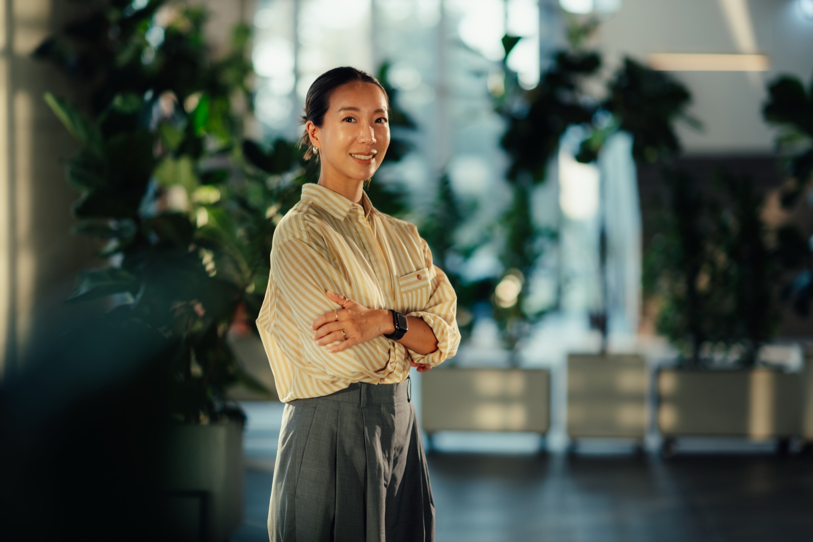 A confident professional standing with arms crossed in a modern office.