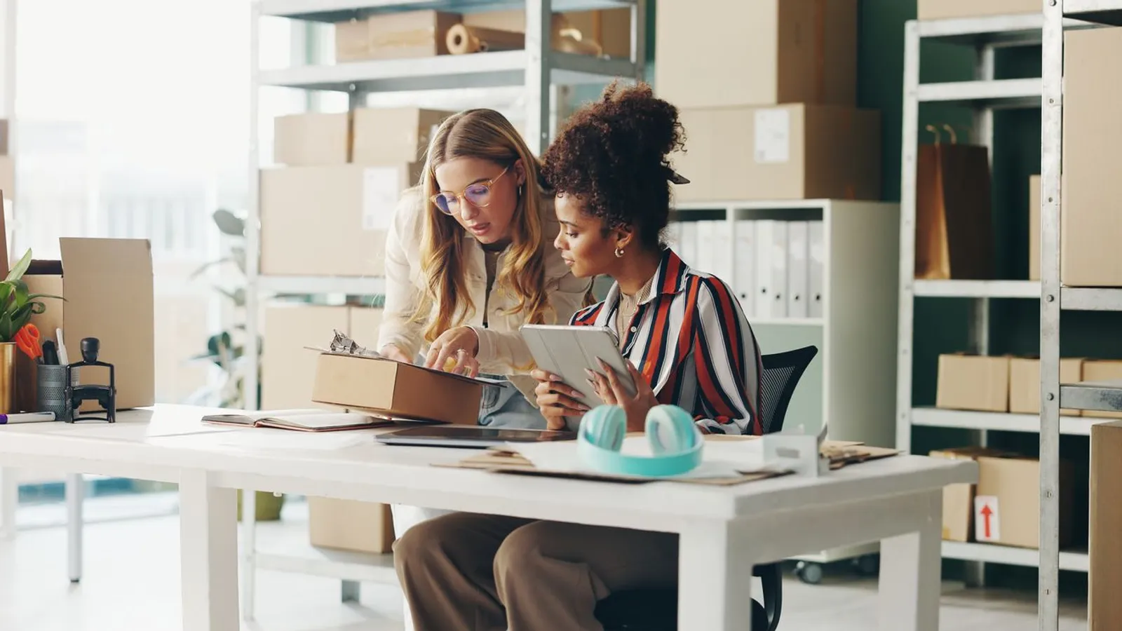 women at worktable checking packaging desk