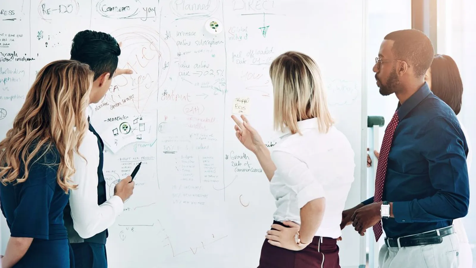 business people grouped in front of whiteboard