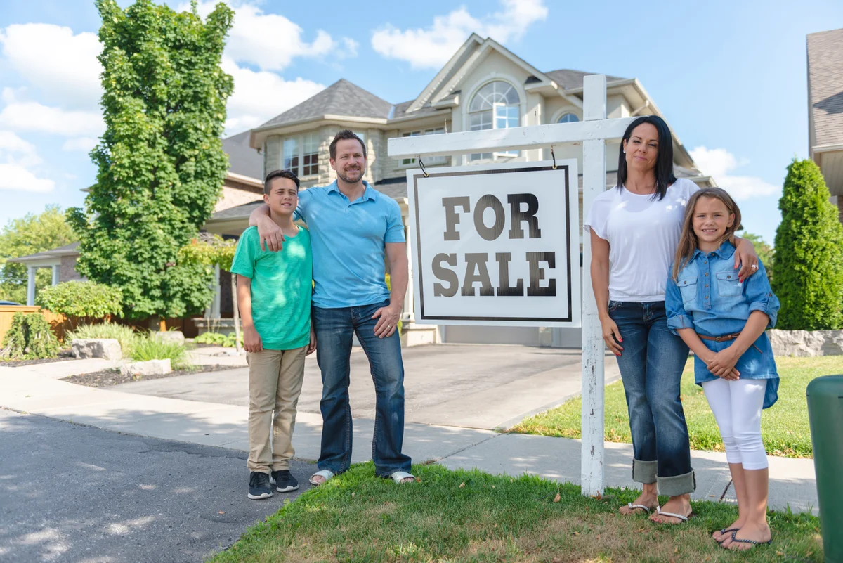 Family poses outside home for sale