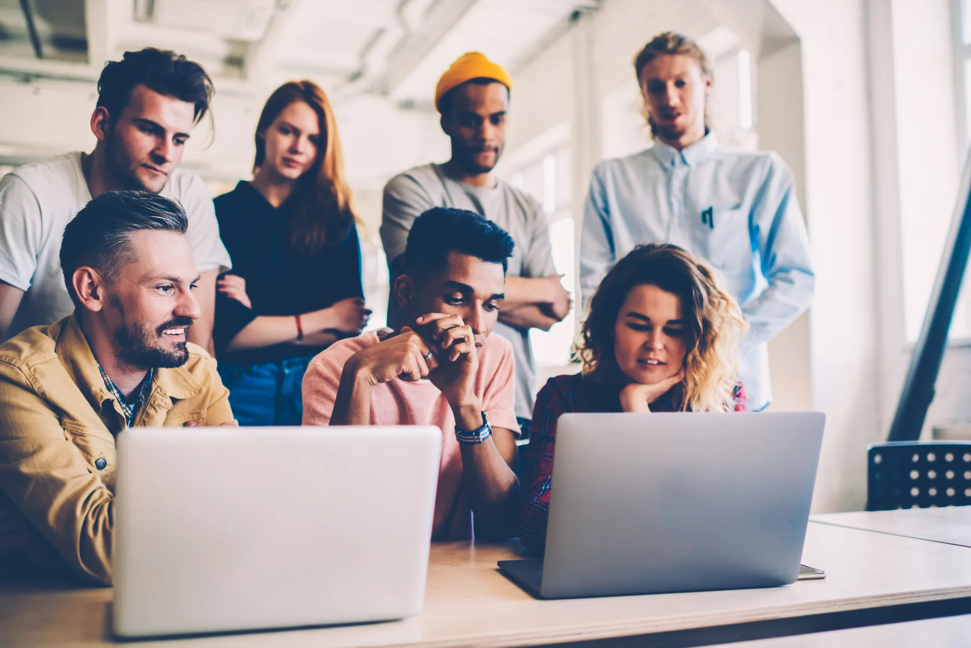 Skilled team of developers using modern technologies for testing application online showing to leader, multiracial young crew of students concentrated on working process watching v