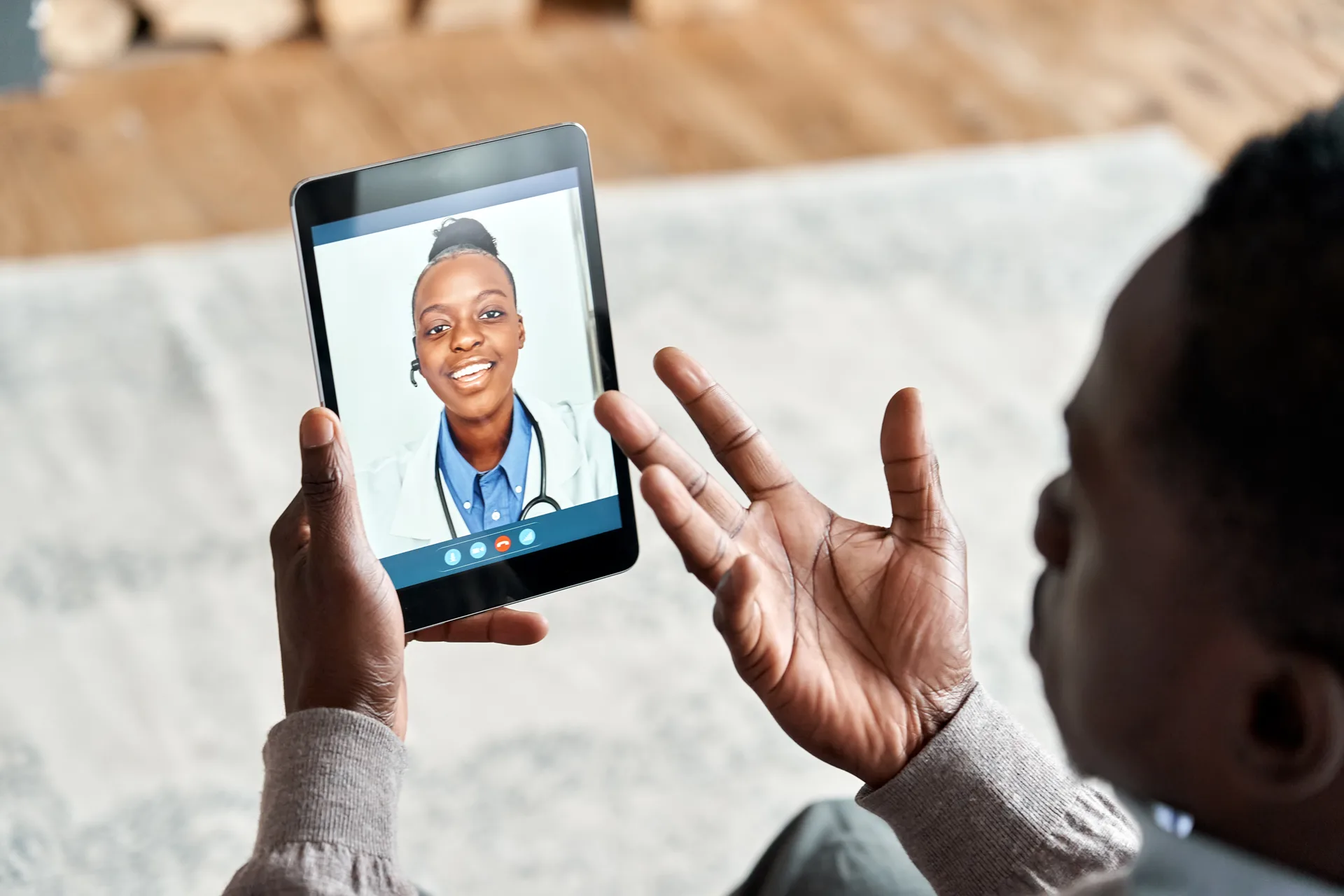 Over shoulder view of african man video calling female virtual doctor consulting patient on tablet at home. Online telemedicine chat visit meeting. Ehealth, telehealth consultation