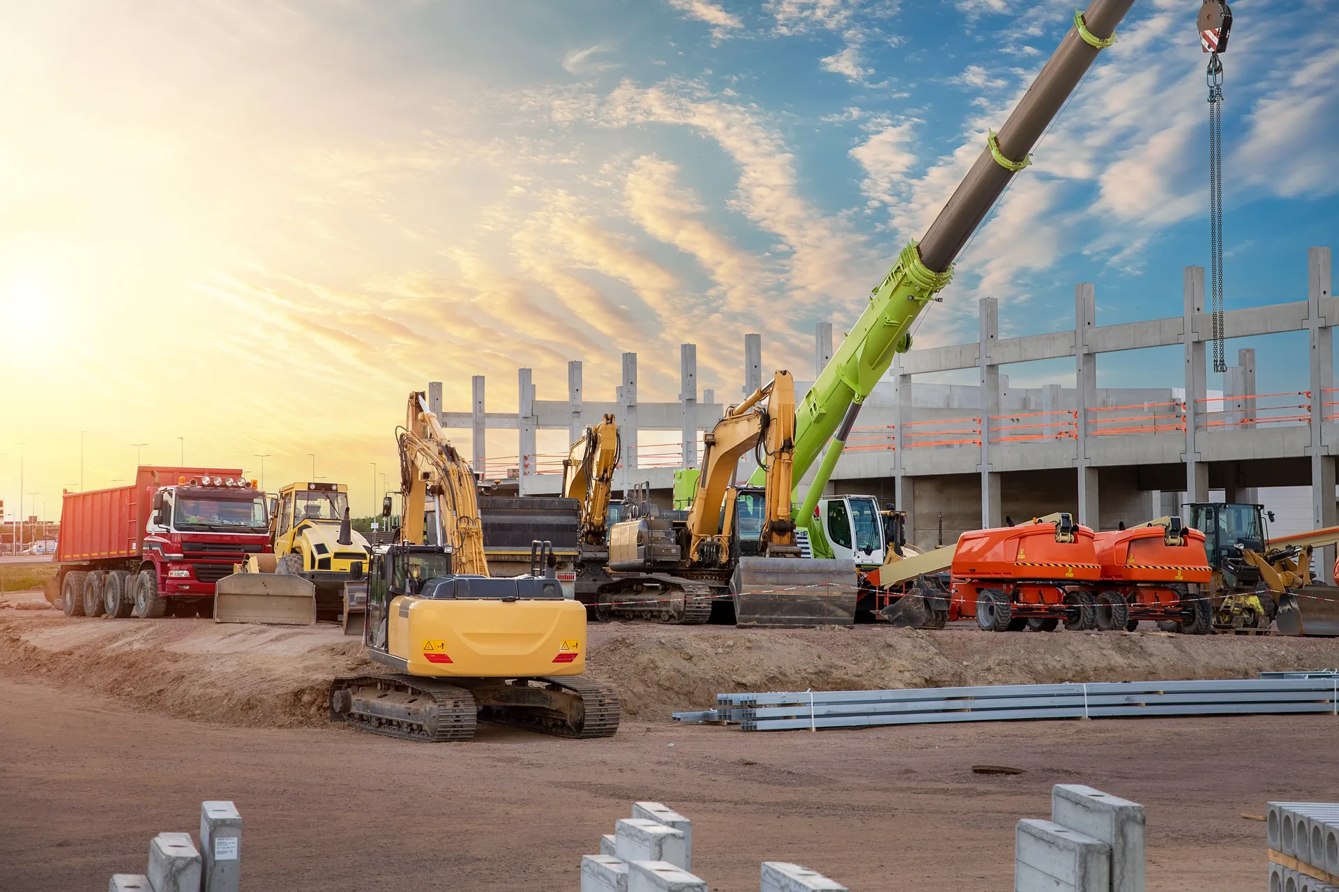 Many different multiclored colorful heavy industrial machinery equipment at construction site parking area against warehouse building city infrastructure development. Commercial ve