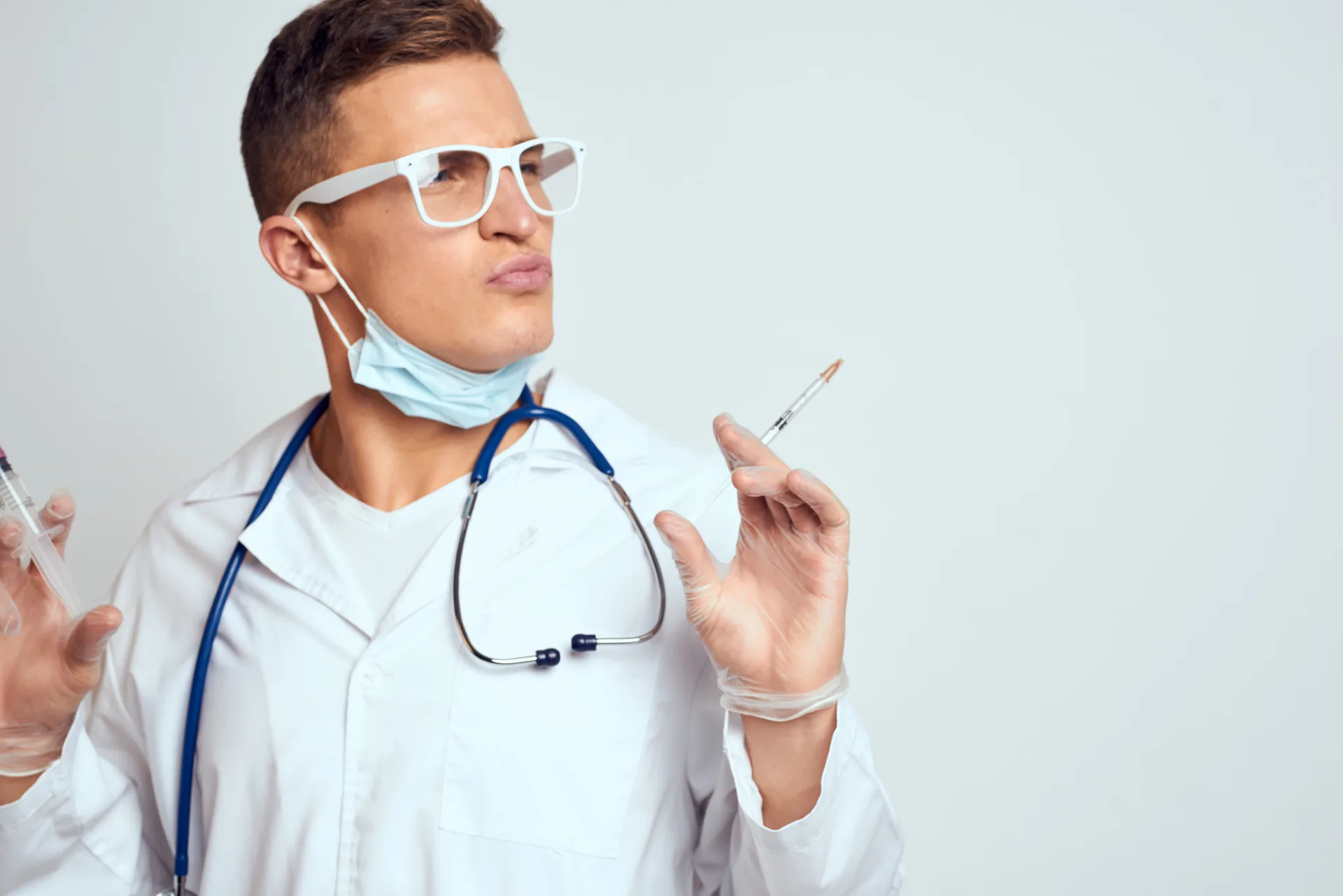 doctor in a medical gown with a stethoscope and glasses on a light background cropped view portrait