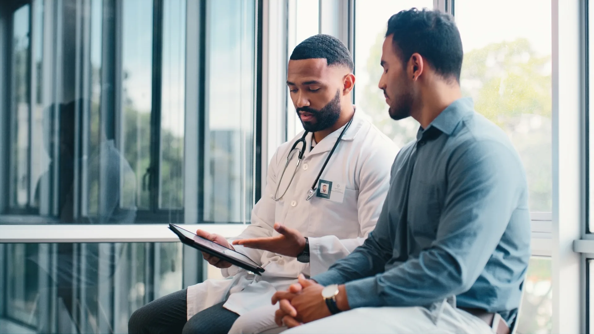 Doctor, men and consultation with patient, tablet and hospital for wellness, advice and medical feedback. People, healthcare and services with report, news and review info on appli