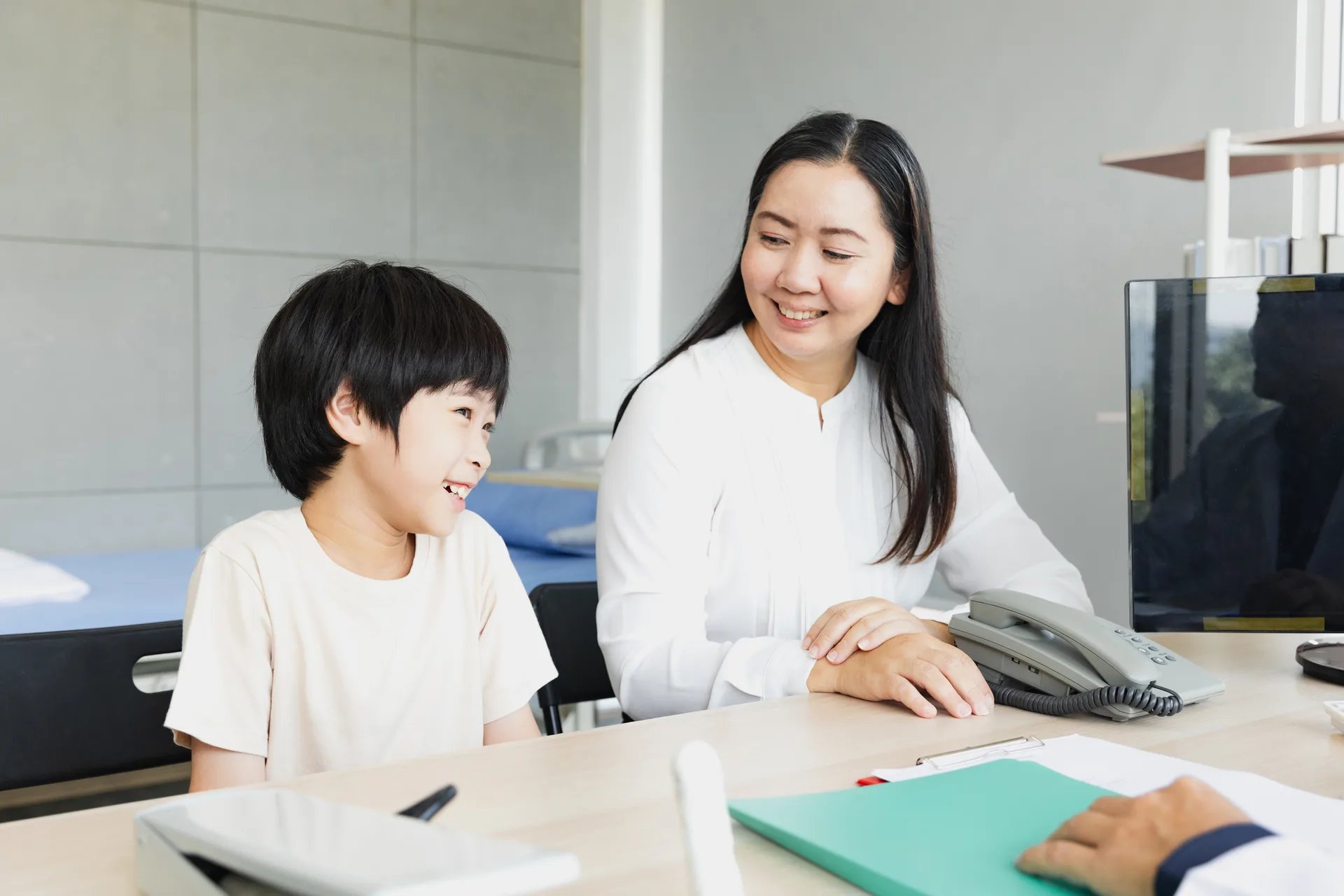 Mother and child interacting with a medical professional in a bright clinic setting during a consultation